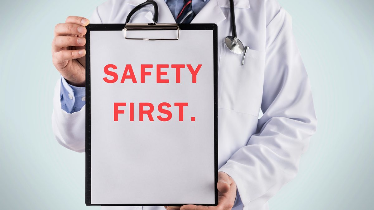 Image featuring a healthcare professional holding up a sign. The sign reads ‘Safety First’.